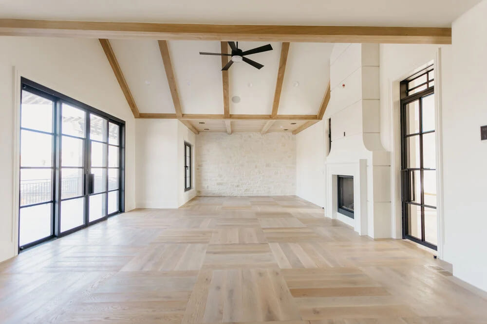 living room with white walls and fireplace with light hardwood flooring and black accents by 10x Builders in Utah