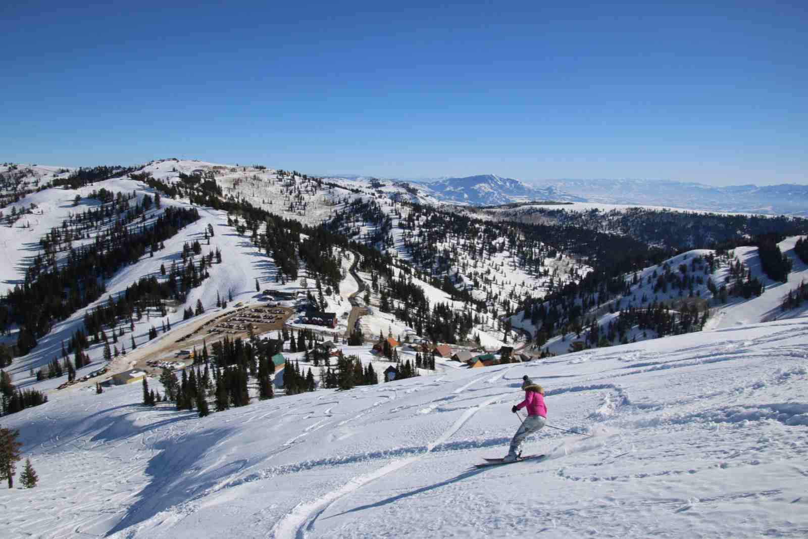 woman in pink jacket skiing on powder mountain - photo by the luxury vacation guide