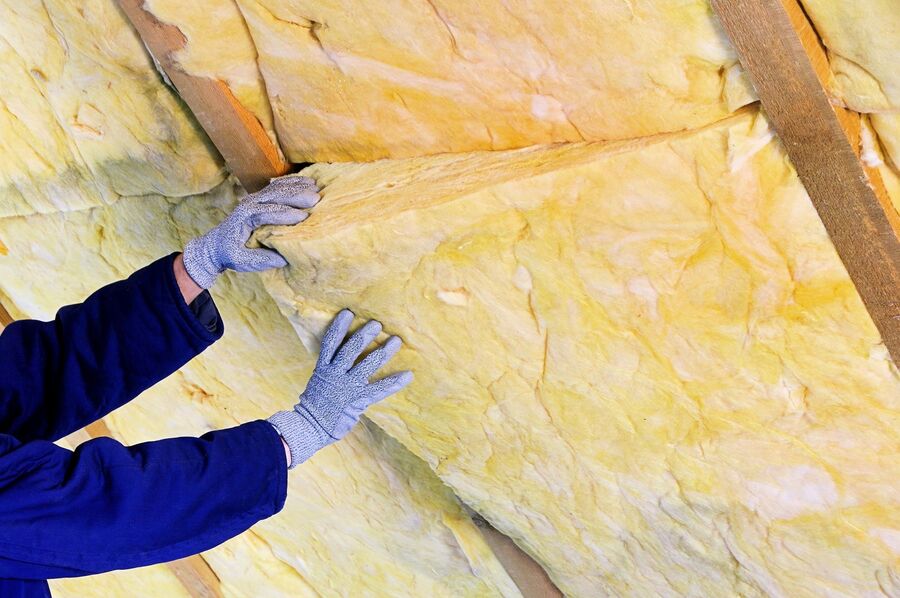 someone installing insulation inside of home with gloves and suit - photo by sdc rigid foam insulation inc