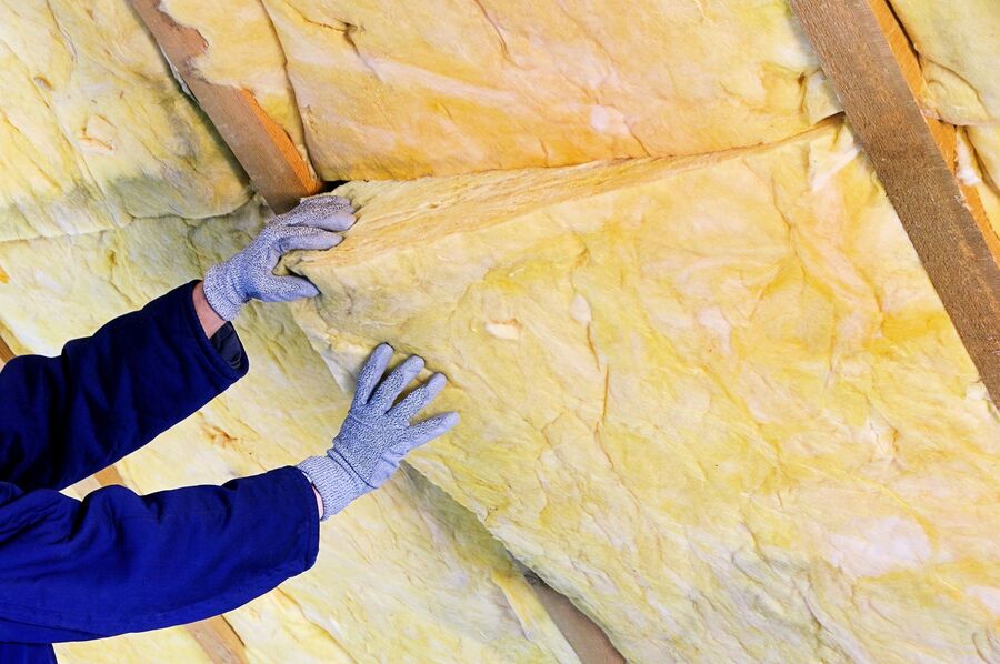 someone installing insulation inside of home with gloves and suit - photo by sdc rigid foam insulation inc