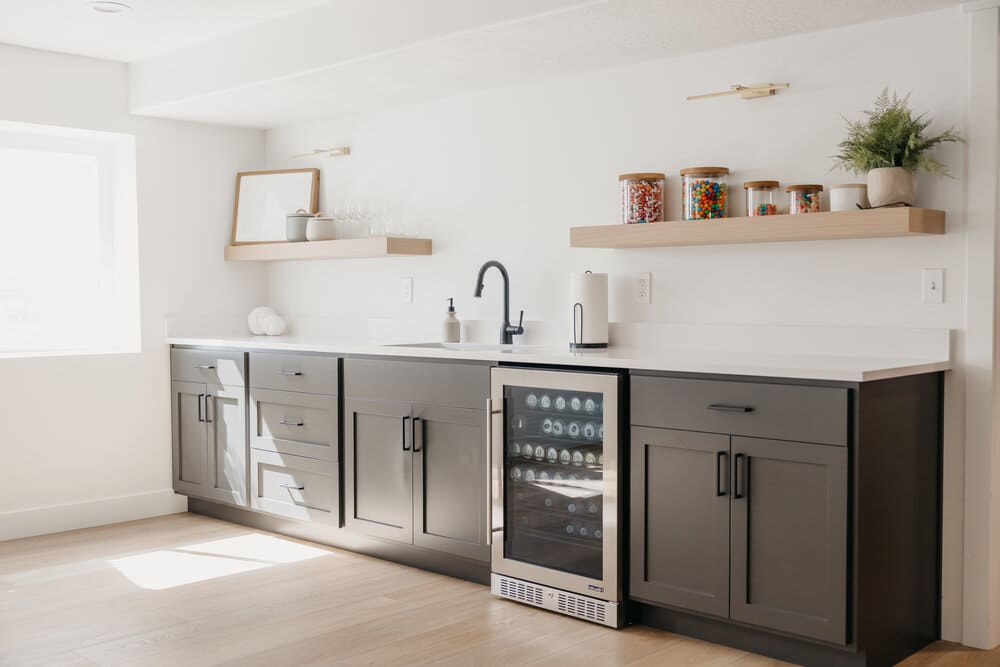 basement kitchenette with beer cooler and white countertops with snack shelving and sink by 10x builders in Utah