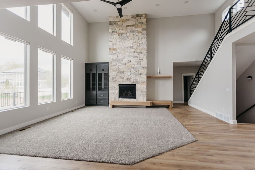 living area with vaulted ceiling and stone fireplace by 10x builders in utah county